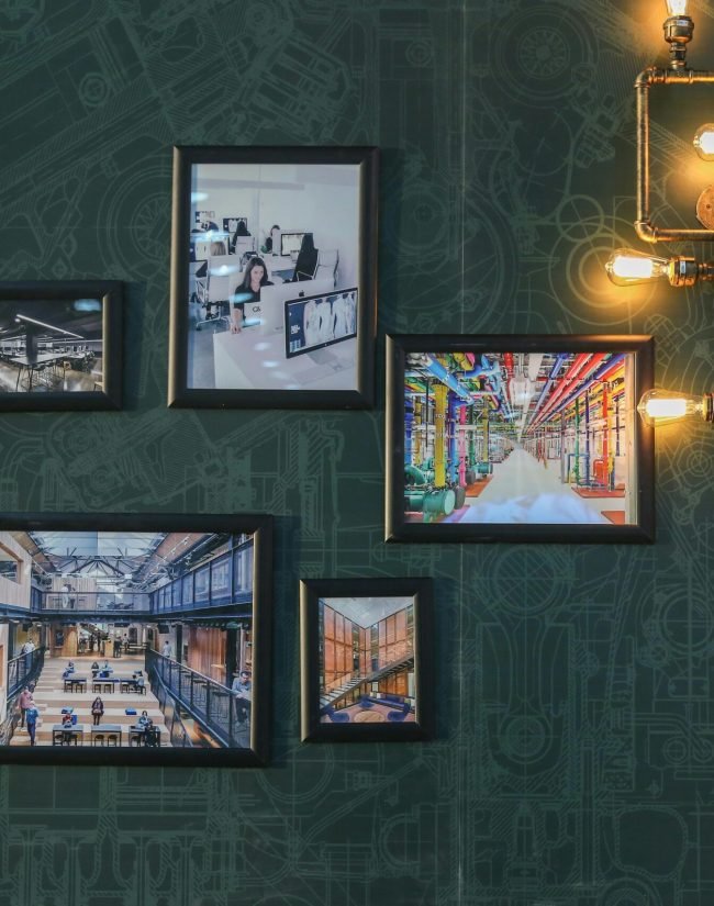 Industrial style wall art with vintage pipe lighting on a green textured wall adds a unique touch.